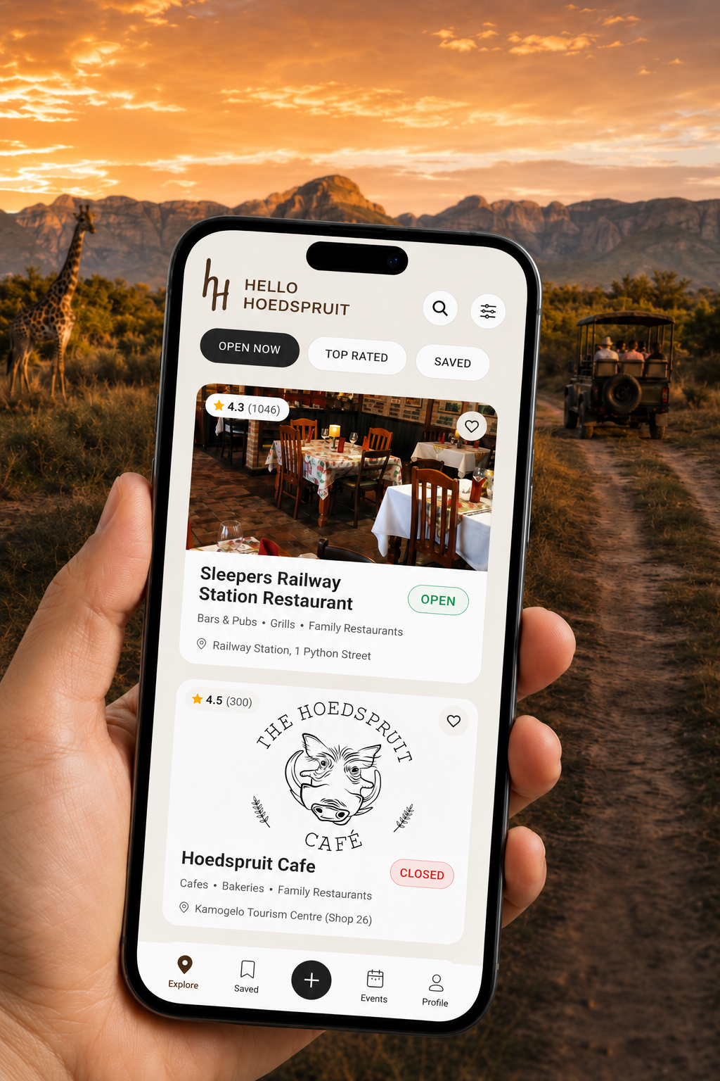 Hello Hoedspruit app open on a phone against a lowveld safari sunset